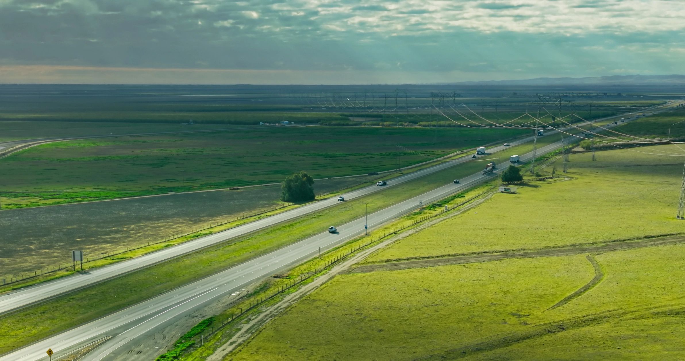 Aerial highway through farmland under dramatic clouds